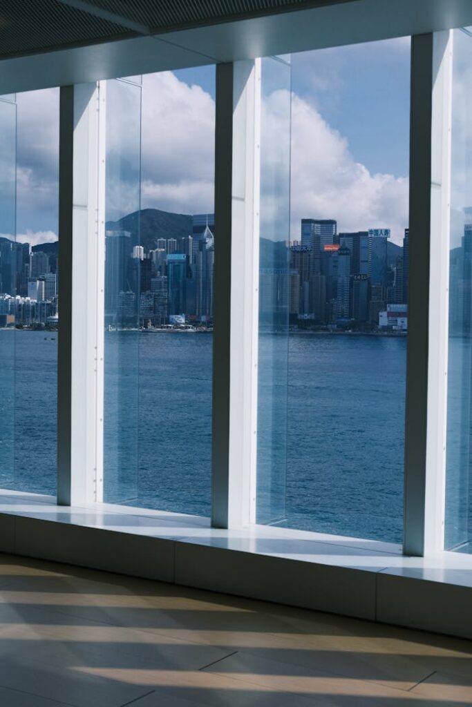 View of Hong Kong skyline through large windows with Victoria Harbor in the foreground.