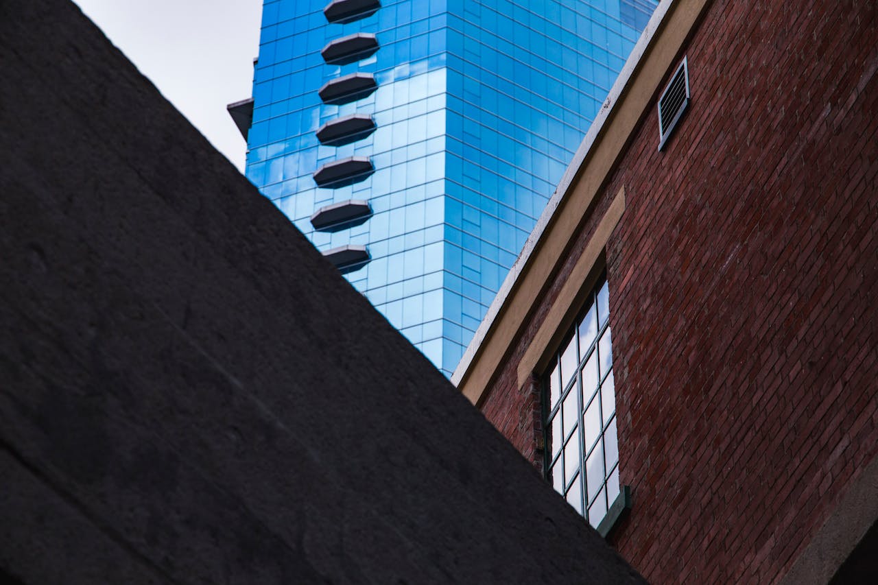 our-story-01 A striking image capturing the contrast between modern glass skyscrapers and traditional brick buildings in Hong Kong.